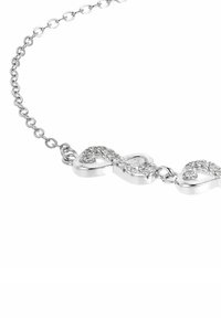Silverfärgad kedjehalsband med tre oändlighetssymboler prydda med små glittrande kristaller mot en vit bakgrund.