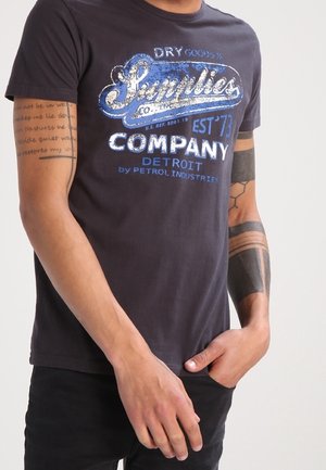 Dunkelgraues Baumwoll-T-Shirt mit einem grafischen Druck in Blau und Silber. Kurze Ärmel, Rundhalsausschnitt und lässiger Schnitt mit sichtbaren Nähdetails.