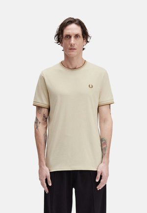 Camiseta de algodón beige con mangas cortas, cuello y puños de manga acanalados en marrón en contraste, con un pequeño logo bordado en el pecho.