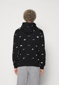 Sudadera con capucha negra con logotipos blancos de Nike repetidos, hecha de tela suave. Cuenta con capucha con cordón y puños y dobladillo acanalados.
