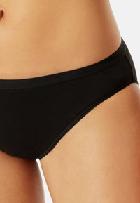 Schwarze Baumwollslips mit glatter Textur und elastischem Bund. Mit einem mittelhohen Schnitt und minimaler Naht für optimalen Komfort.