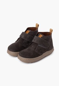 Stivaletti alla caviglia in suede grigio scuro con un cinturino in Velcro, dettagli beige e una fodera interna testurizzata; suola in gomma con cuciture visibili.