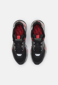 Chaussures de sport noires avec des accents rouges et gris, tige en mesh, bout rond, lacets et détail de logo sur la languette et les semelles intérieures.