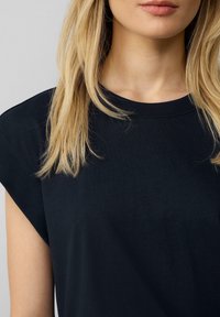 Sort bomulds t-shirt med rund hals, korte, afslappede ærmer og glat tekstur, med et enkelt, minimalistisk design.