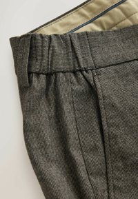 Gray textured trousers with a pleated waistband and contrasting inner lining. Features subtle patterns and a tailored design.