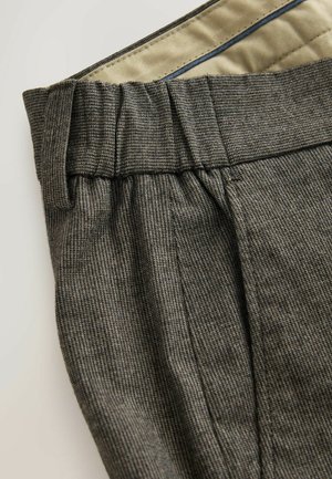 Grå teksturerede bukser med plissert liv og kontrasterende indvendig for. Har subtile mønstre og et skræddersyet design.