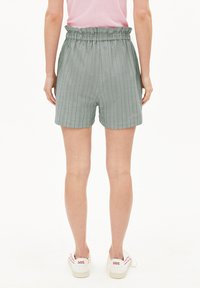 Grau karierte Shorts mit einem gerafften elastischen Bund, aus leichtem Stoff gefertigt, bis zur Mitte des Oberschenkels reichend, kombiniert mit weißen Turnschuhen.