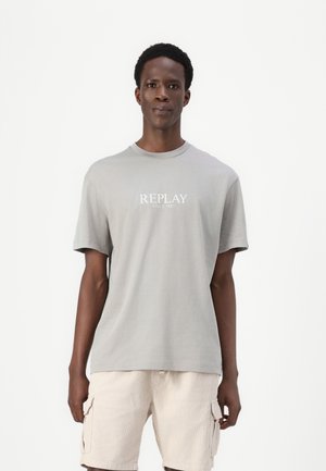 Camiseta de algodón gris con cuello redondo y mangas cortas, que presenta una impresión blanca de "REPLAY SINCE 1981" en el frente.