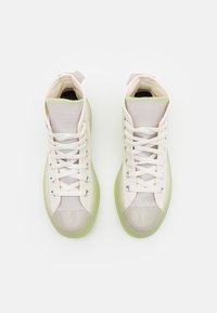 Vysoké tenisky s vrchnou časťou z mesh materiálu v off-white farbe, s polopriehľadnou zelenou podrážkou a hladkými šnúrkami. Súčasťou sú aj strieborné očká a úchyty.