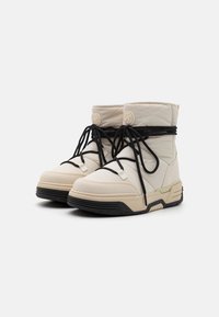 Witte gewatteerde laarzen met zwarte veters, gestructureerde panelen en een contrasterende zwarte zool. Heeft een rond logo en een iets verhoogde hak.