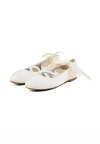 Ballerines blanches avec des brides élastiques croisées et de longs rubans noués autour de la cheville, présentées sur fond blanc.