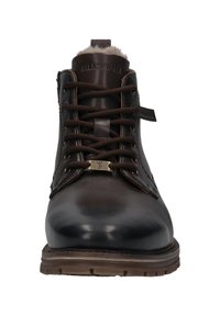 Botas de cuero marrón con cordones, acabado liso, lengüeta texturizada y forro de borreguito. Presenta un detalle metálico y suela de goma.