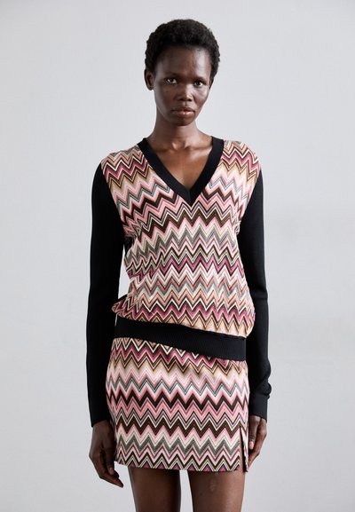 Strikket kjole med sorte ærmer og udskæring, prydet med et flerfarvet zigzag mønster i pink, guld og brun, med en sideslids.