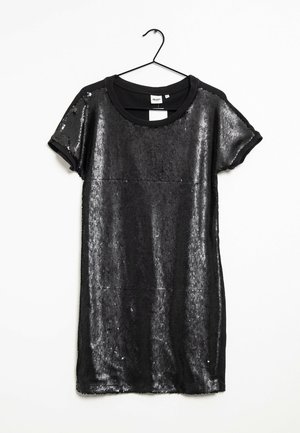 Robe courte noire à sequins avec manches courtes suspendue sur un cintre noir sur fond blanc.