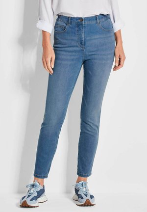 Lichtblauwe spijkerbroek met een slim fit ontwerp, vijf zakken, subtiele stikdetails en een knoopsluiting bij de taille, gecombineerd met blauwe sneakers.