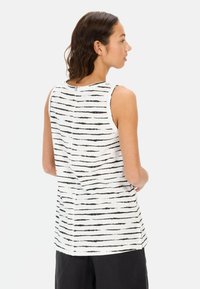 Biała bezrękawnikowa bluzka z czarnymi poziomymi paskami, o prostym kroju, wykonana z miękkiego materiału, z detalem zapięcia z tyłu.