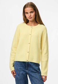 Gaiši dzeltena ribotā džempera jaka ar apaļu kaklu, garām piedurknēm un pogu aizdari, kurai ir dekoratīvi sudraba toņa akcenti.