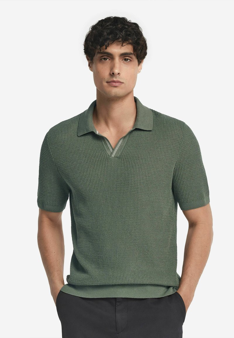 Grön kortärmad polo shirt tillverkad av strukturerad stickad tyg, med en krage och V-hals samt subtila randdetaljer.