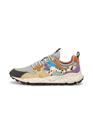 Low-top sneaker with chunky speckled sole, multicolor panels including grey, beige, purple, blue, and animal print accents, and white laces.