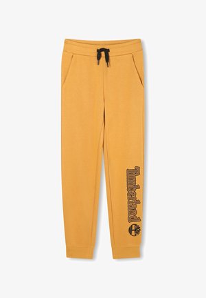 Gele joggingbroek van zacht stof, voorzien van zijzakken en een zwarte trekkoord. "Timberland" logo gedrukt op het linkerbeen.