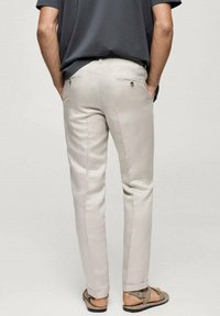 Lichtbeige broeken met een slim fit, met een gladde textuur, twee achterzakken met knopen en details aan de zijnaad. Casual uitstraling, gecombineerd met sandalen.