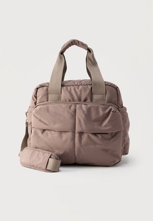 Sac fourre-tout beige doux et rembourré avec deux poignées et une bandoulière amovible, doté de plusieurs compartiments zippés.