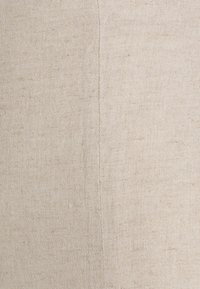 Přírodní lněná tkanina ve světlé béžové barvě se jemnou strukturou. Obsahuje vertikální šev, což jí dodává jednoduchý a neutrální vzhled.