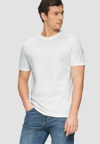 Weißes Kurzarm-Baumwoll-T-Shirt mit Rundhalsausschnitt, locker sitzend präsentiert. Kombiniert mit blauen Jeans.