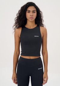 Zwarte cropped tanktop van gladde stof, met een ronde halslijn en het merkniveau "MISAGA®" in het wit op de borst. Bijpassende zwarte leggings.