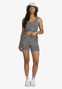 Black and white striped crop top and shorts set made from textured fabric. Accented with a white bucket hat featuring blue branding.