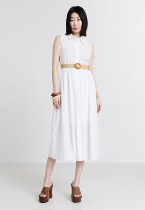 Weißes, ärmelloses A-Linien-Kleid mit Lochmuster, Kragenkragen, tailliert durch einen gewebten Gürtel. Braune Plateau-Schuhe und Holzarmbänder.