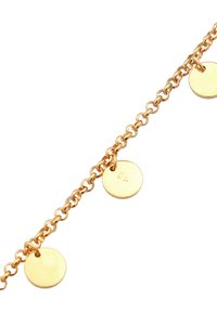Bracciale in tono oro con una delicata catena caratterizzata da tre dischi circolari, ognuno dei quali presenta una piccola incisione, evidenziando il suo design minimalista.