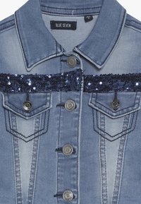 Giacca di jeans leggera blu con un nastro di paillettes blu navy sul petto, con bottoni argentati e due tasche frontali con dettagli cuciti.