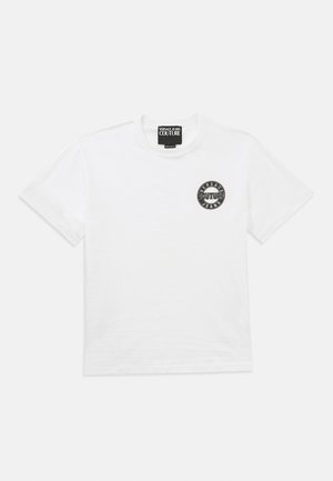 Weißes Baumwoll-T-Shirt mit einem runden schwarzen Logo und dem Text "Versace Couture Jeans" auf der linken Brustseite. Kurze Ärmel und Rundhalsausschnitt.
