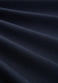 Donkerblauwe gemêleerde stof met een ribbelpatroon, met zachte plooien en een gladde oppervlakte. Geschikt voor verschillende textieltoepassingen.