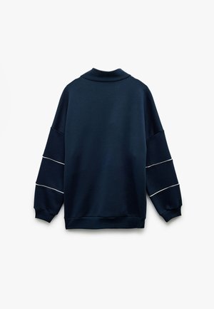 Navy sweatshirt with a high collar, loose fit, and dropped shoulders. Features white horizontal stripes on sleeves. Soft fabric texture.