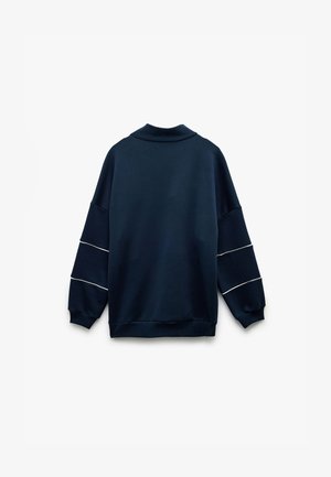 Granatowy sweter z wysokim kołnierzem, luźnym krojem i opuszczonymi ramionami. Posiada białe poziome paski na rękawach. Miękka tekstura tkaniny.