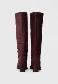 Bottes hautes bourgogne en fausse fourrure texturée, avec un talon bloc et des semelles noires lisses, au design élégant et ajusté.
