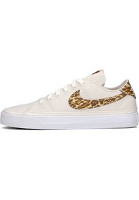 Zapatillas de lona blancas con un logo de Nike en estampado de leopardo marrón, cordones blancos y una suela de goma texturizada.