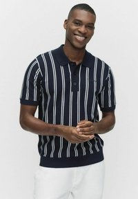 Mörkblå stickad polo med vita vertikala ränder, med krage och treknappsknäppning; figurnära design med ribbstickad nederkant och muddar.