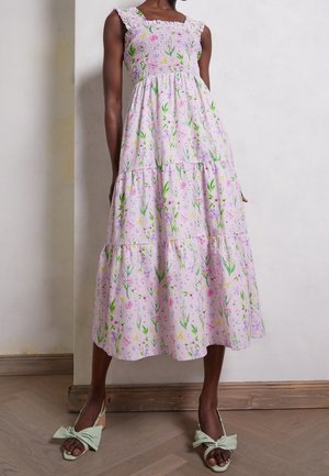 Vestido midi de flores con falda en capas y cuerpo fruncido, que presenta un fondo lila y estampados botánicos en verde, rosa y amarillo. Incluye tirantes rizados.
