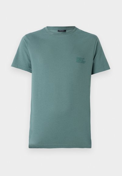 T-shirt vert menthe en coton, présentant un col rond et des manches courtes. Détail de texte en petite taille dans une teinte plus foncée sur la poitrine.
