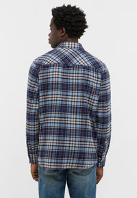 Marineblauwe plaid shirt met blauw en beige ruitpatronen, button-down kraag en lange mouwen. Gemaakt van een zachte, gestructureerde stof.