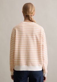 Bluza w paski wykonana z miękkiego materiału, z pomarańczowymi i białymi poziomymi paskami, ściągaczami na mankietach oraz luźnym krojem. Odpowiednia do codziennego noszenia.