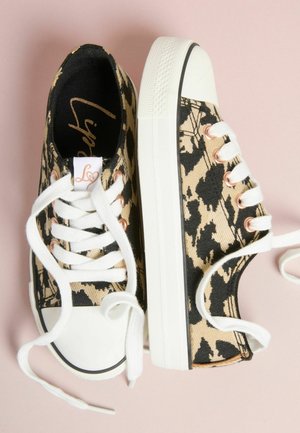 Tenisówki z materiału płóciennego w beżowo-czarny wzór w panterkę, białe gumowe podeszwy i metalowe przelotki. Posiadają białe sznurowadła oraz metkę z logo.