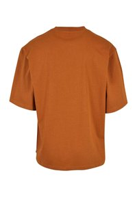 Tricou de culoare ruginită, cu mâneci scurte, de tip crew neck și croială lejeră. Fabricat din bumbac moale, cu o textură netedă.