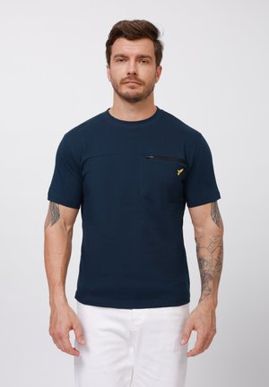 T-shirt à manches courtes bleu marine en tissu lisse, avec une poche poitrine zippée et un accent logo jaune.