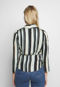 Pasiasta bluzka w odcieniach miętowym, beżowym i czarnym; z długimi rękawami, kołnierzykiem i dopasowanym talią, wykonana z lekkiego materiału.