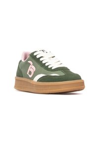 Zapatilla verde con un upper texturizado, detalles blancos, logo rosa y suela de goma. Presenta cordones planos y una lengüeta acolchada.