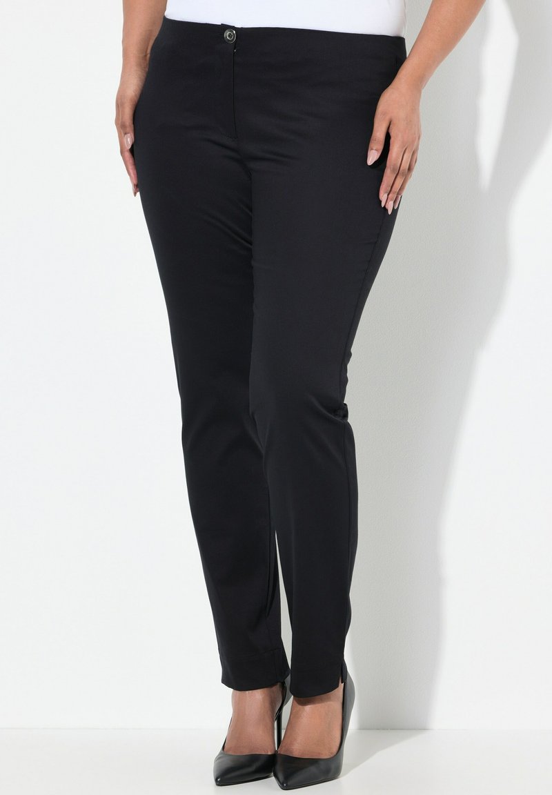 Schwarze, enganliegende Hosen aus glattem Stoff, mit einem vorderen Knopfverschluss und knöchellanger Gestaltung, kombiniert mit schwarzen spitzen Absätzen.